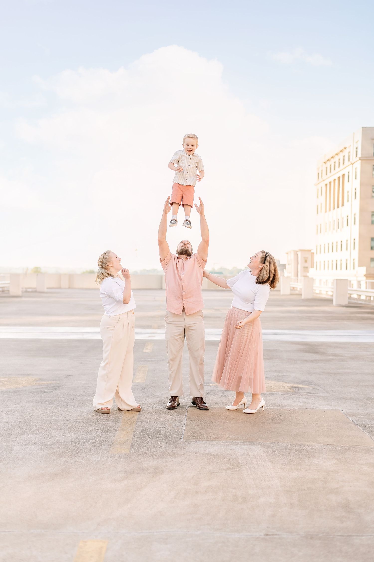 Family members in matching pastel outfits play together on an open rooftop.