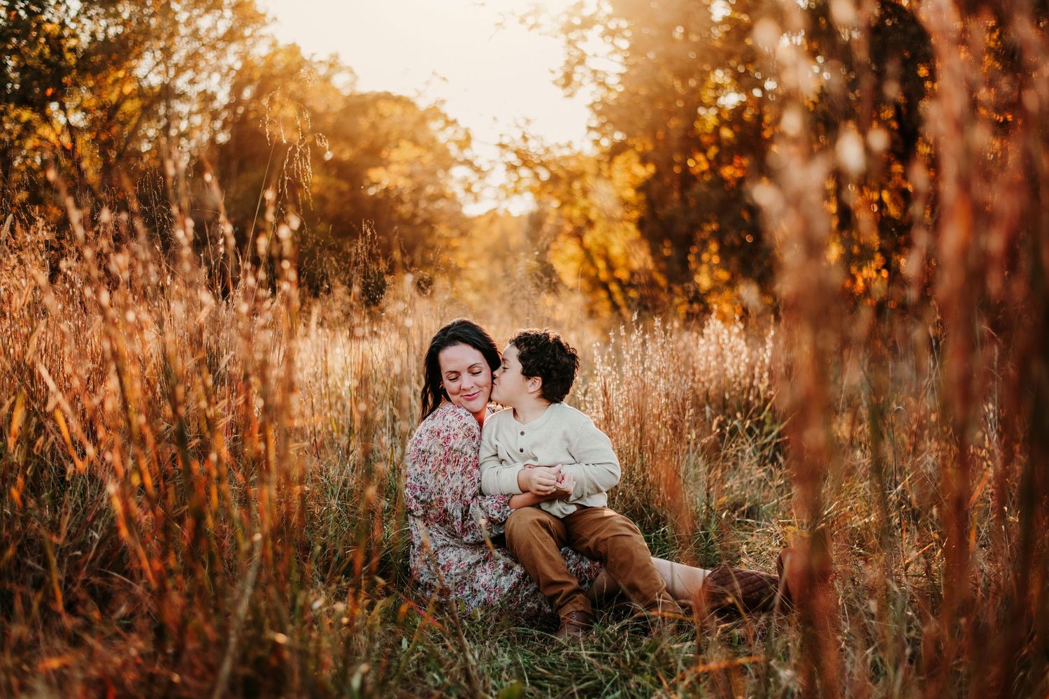 Warm sunset photography session among tall grasses and autumn trees.