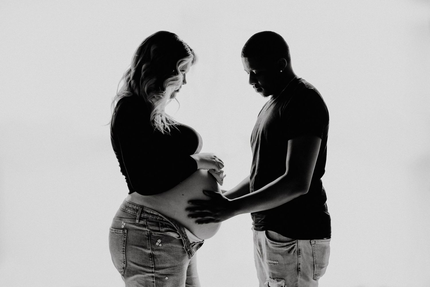 Artistic black and white maternity photo of couple touching pregnant belly.