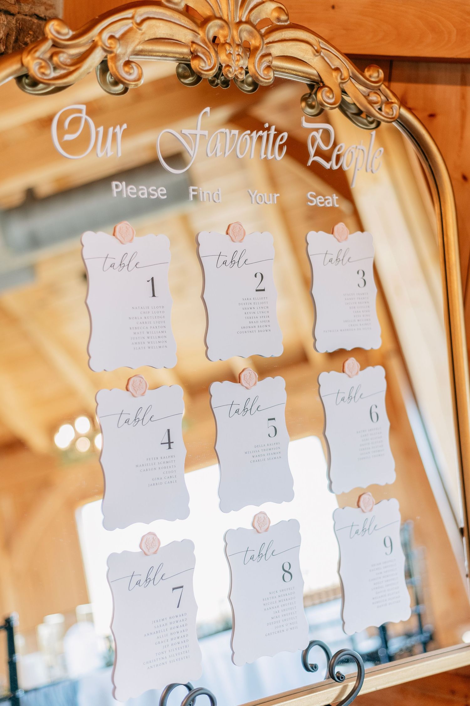 Elegant wedding seating chart displayed on a vintage gold mirror with table cards reading Our Favorite People.