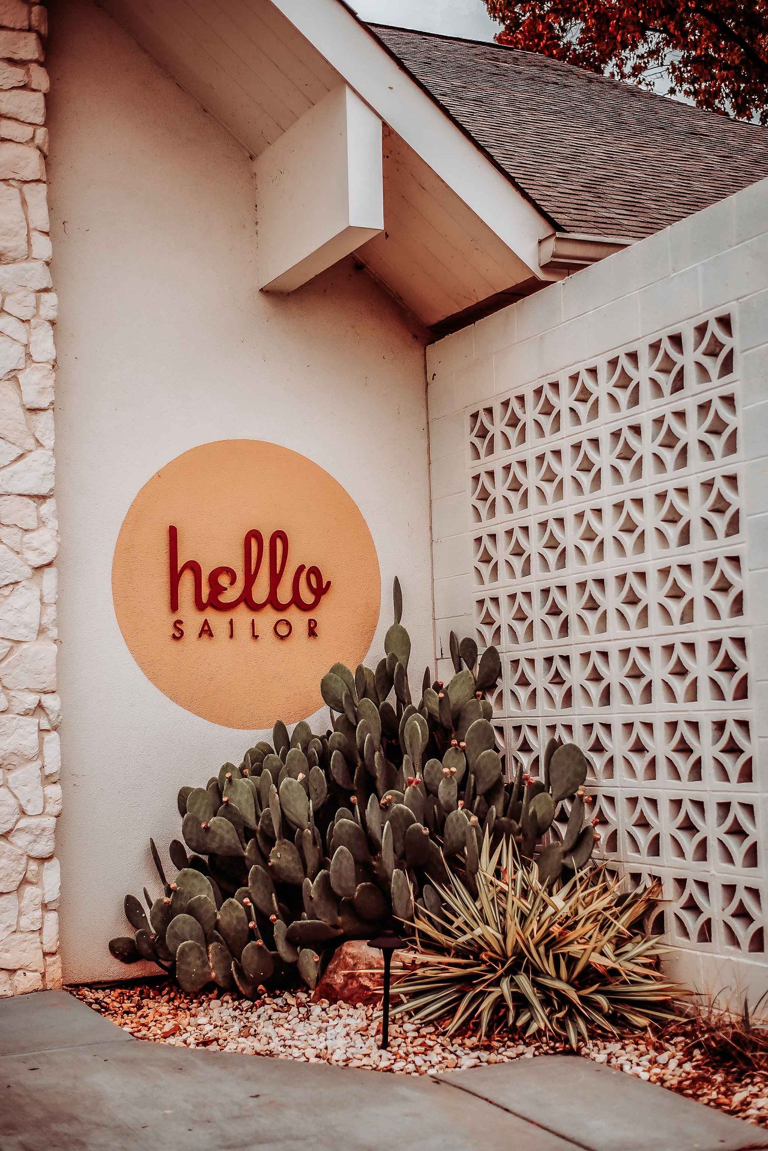 Hello Sailor restaurant exterior with cactus garden, decorative lattice wall, and circular logo sign.