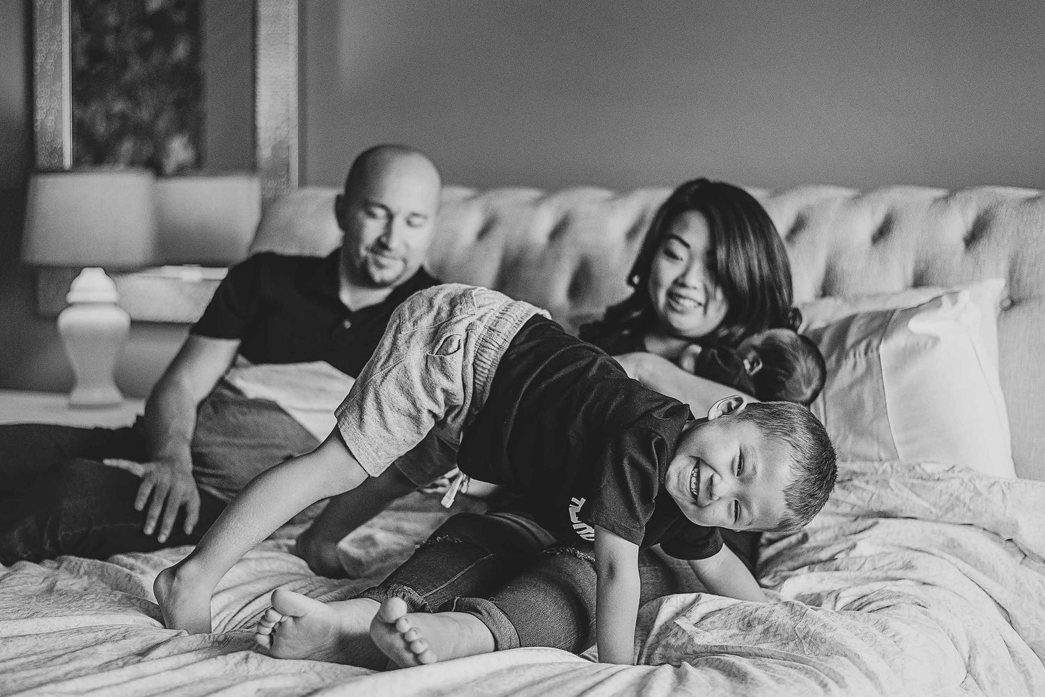 Black and white photo series showing tender moments between parent and child resting together in bed.