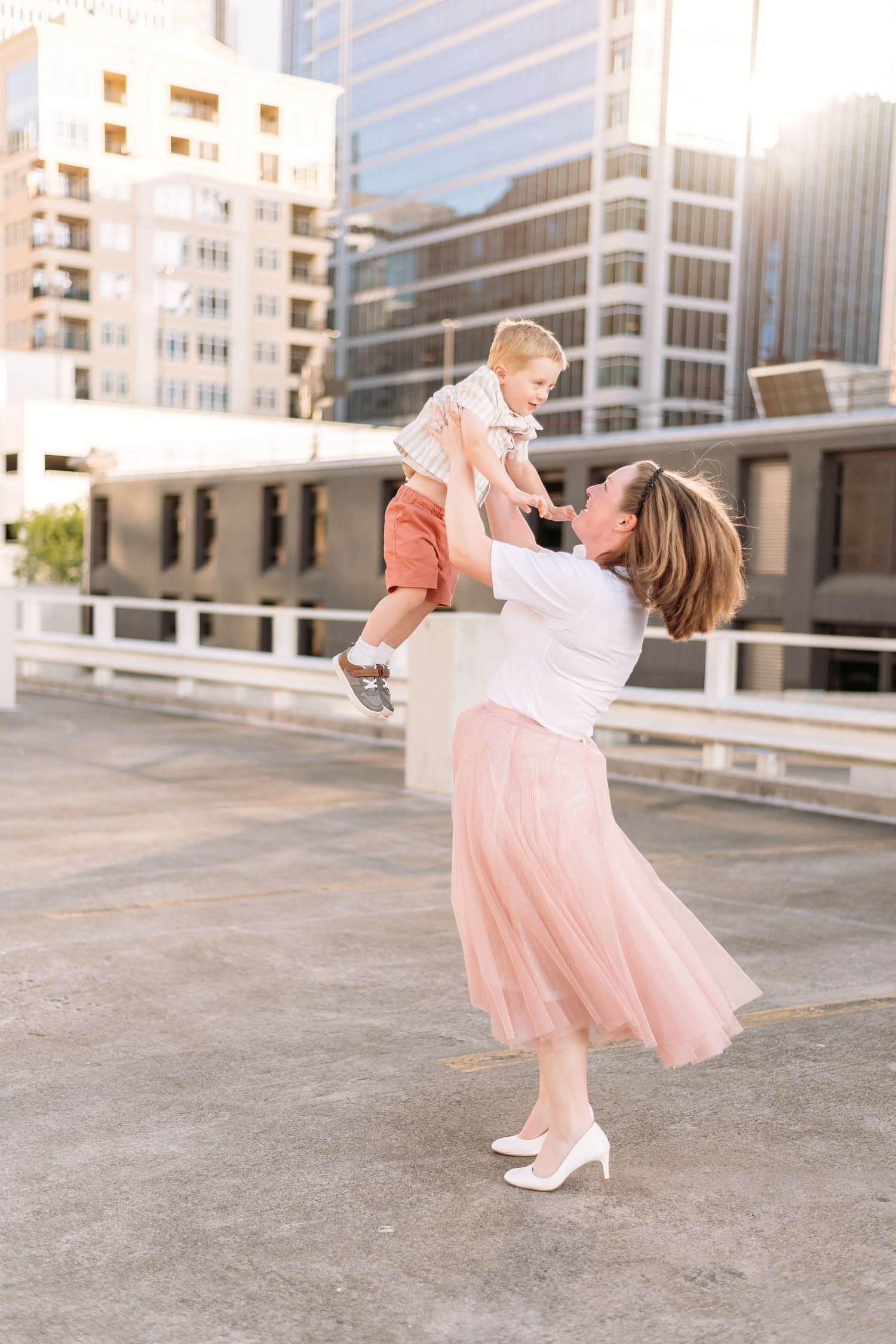 Joyful family moments captured in soft pink tones during a rooftop photoshoot.