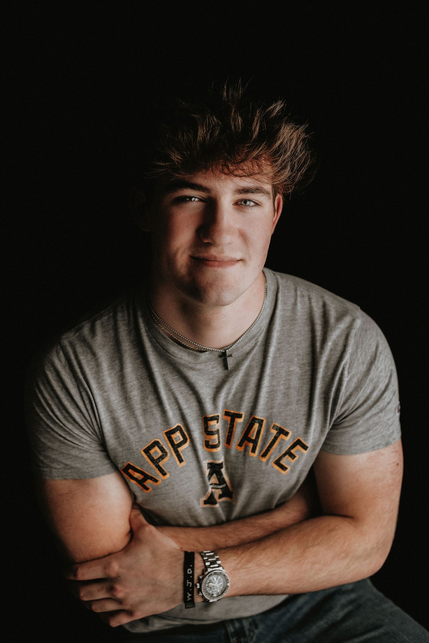 Portrait of an athletic young person in a gray t-shirt with text against dark background.