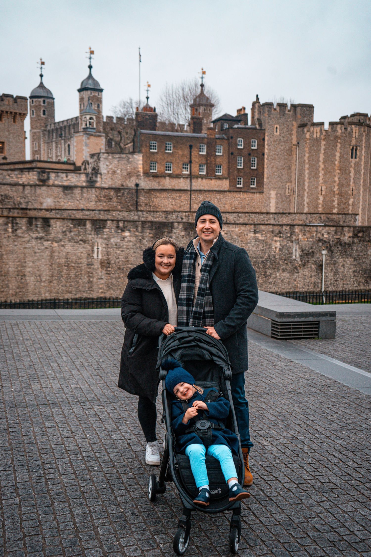 Family of three posing in London smiling at the camera.