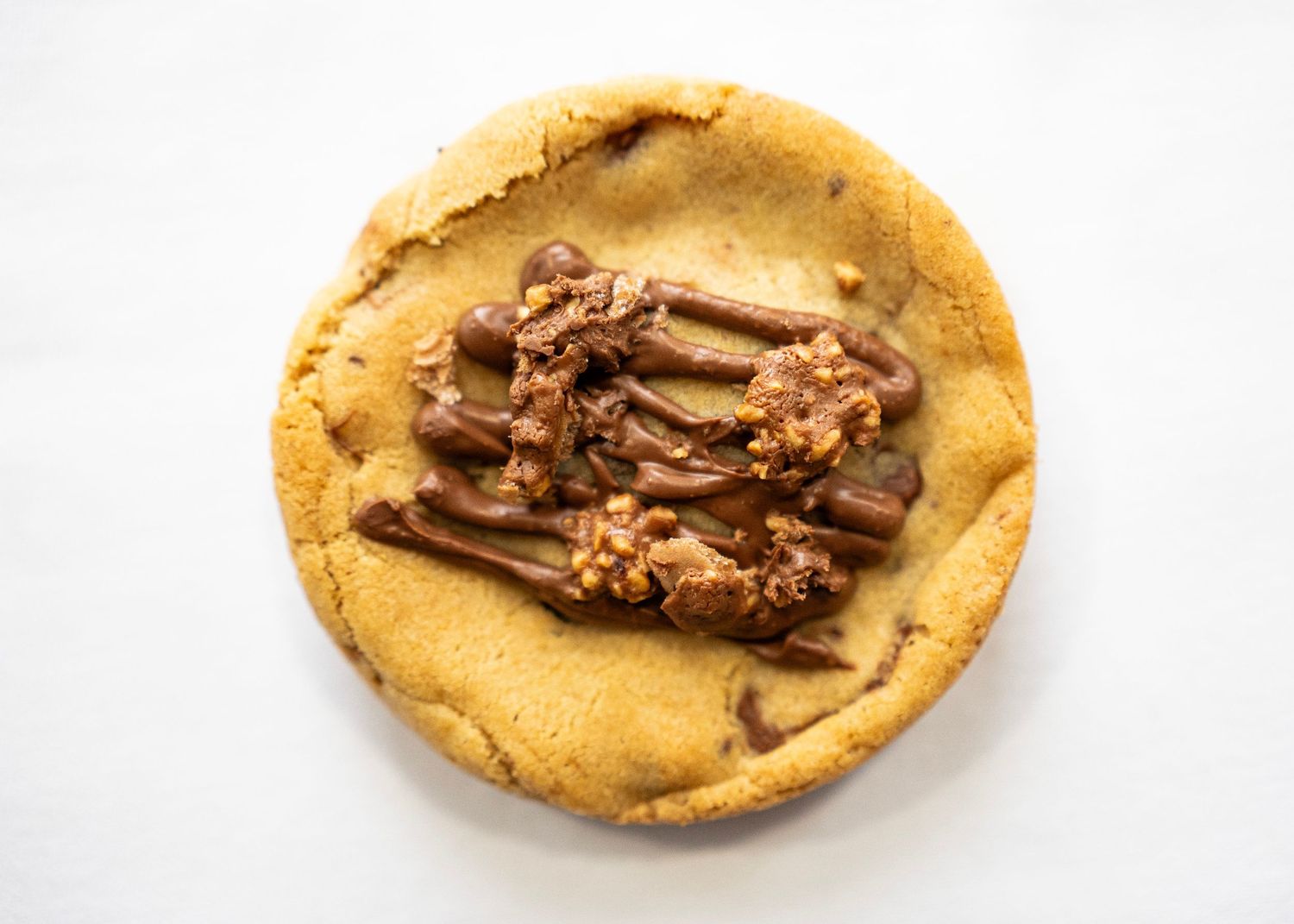 A photo of a large stuffed cookie with chocolate drizzle. A delicious baked good photographed for Wicked Whisk bakery.