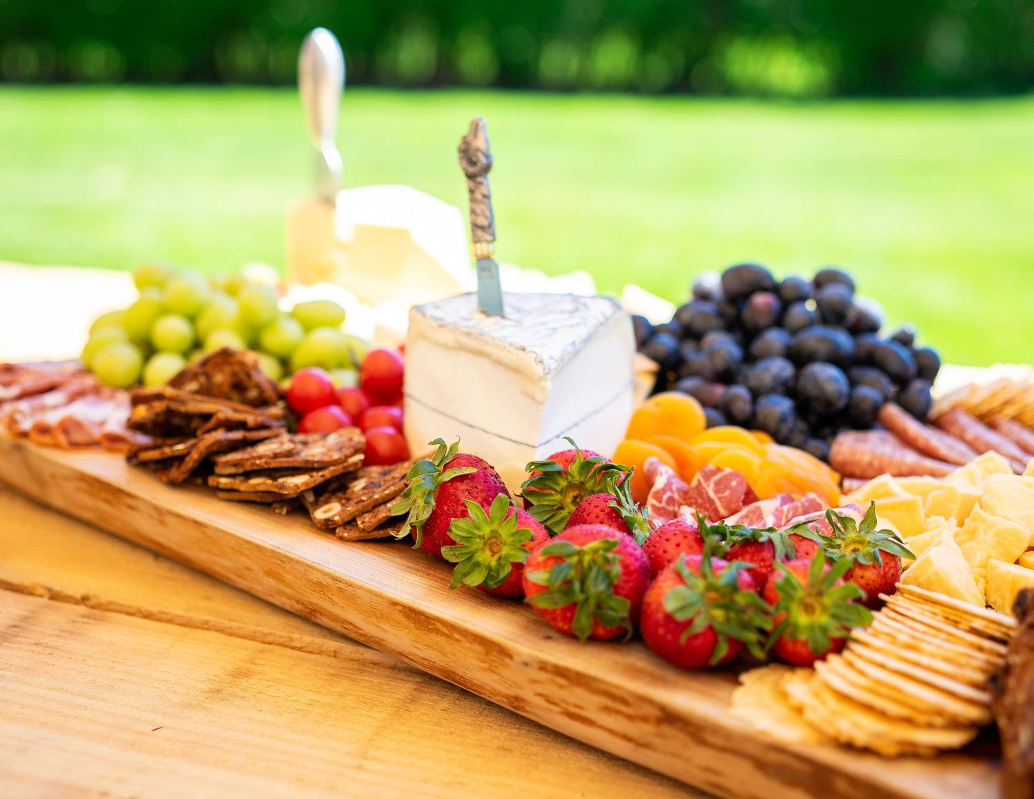 Event catering photo of gourmet cheeses and crackers with strawberries on a wooden board., Made by a private chef for a catering event.
