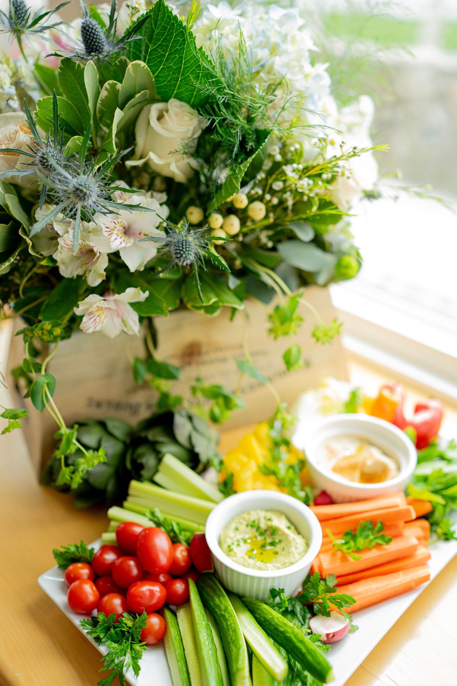 A white platter laden with chef-curated cherry tomatoes, cucumber sticks, celery, carrot sticks, and bell pepper slices elegantly placed.