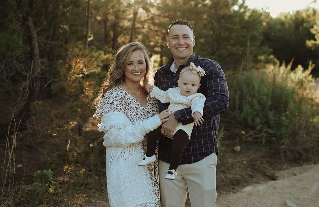 Family of three posing during golden hour smiling at the camera.