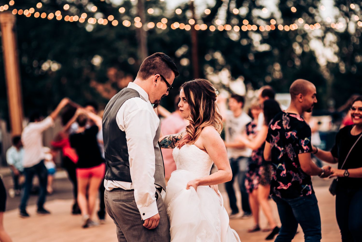 A romantic dance at an outdoor wedding reception with string lights overhead.