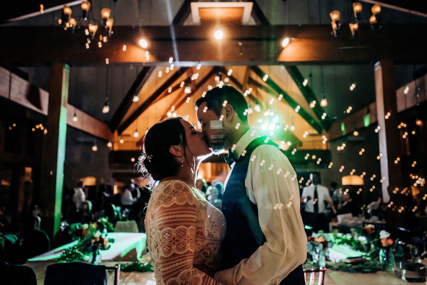 Couple sharing an intimate dance moment under dramatic lighting and falling confetti at their reception.
