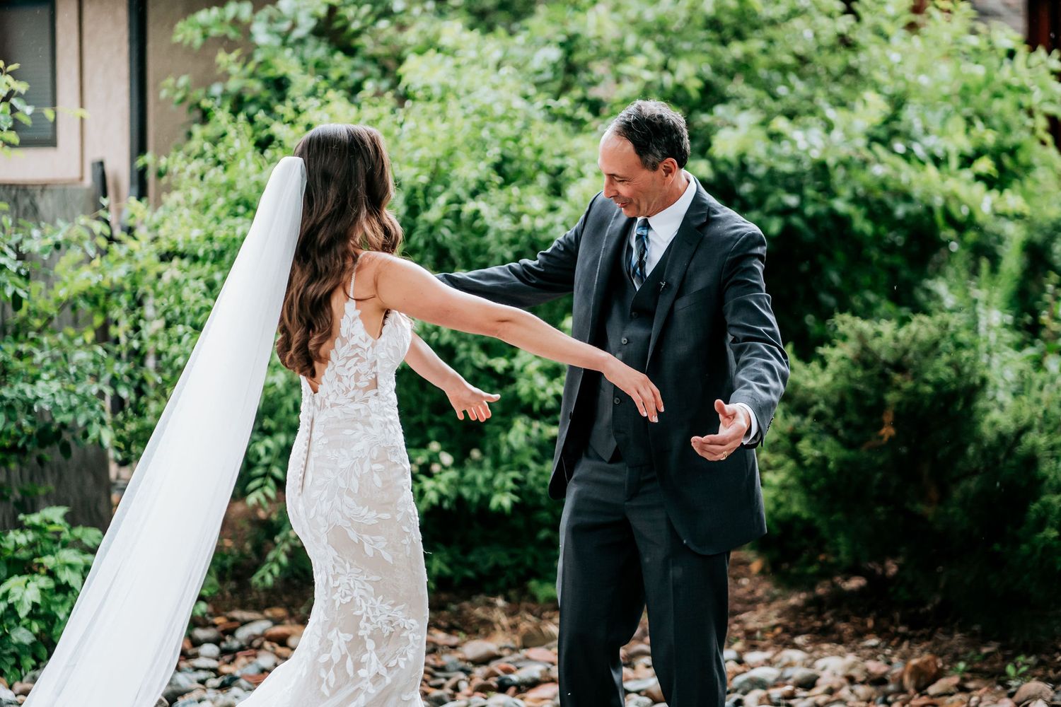 Couple dancing joyfully in an outdoor garden setting surrounded by greenery.
