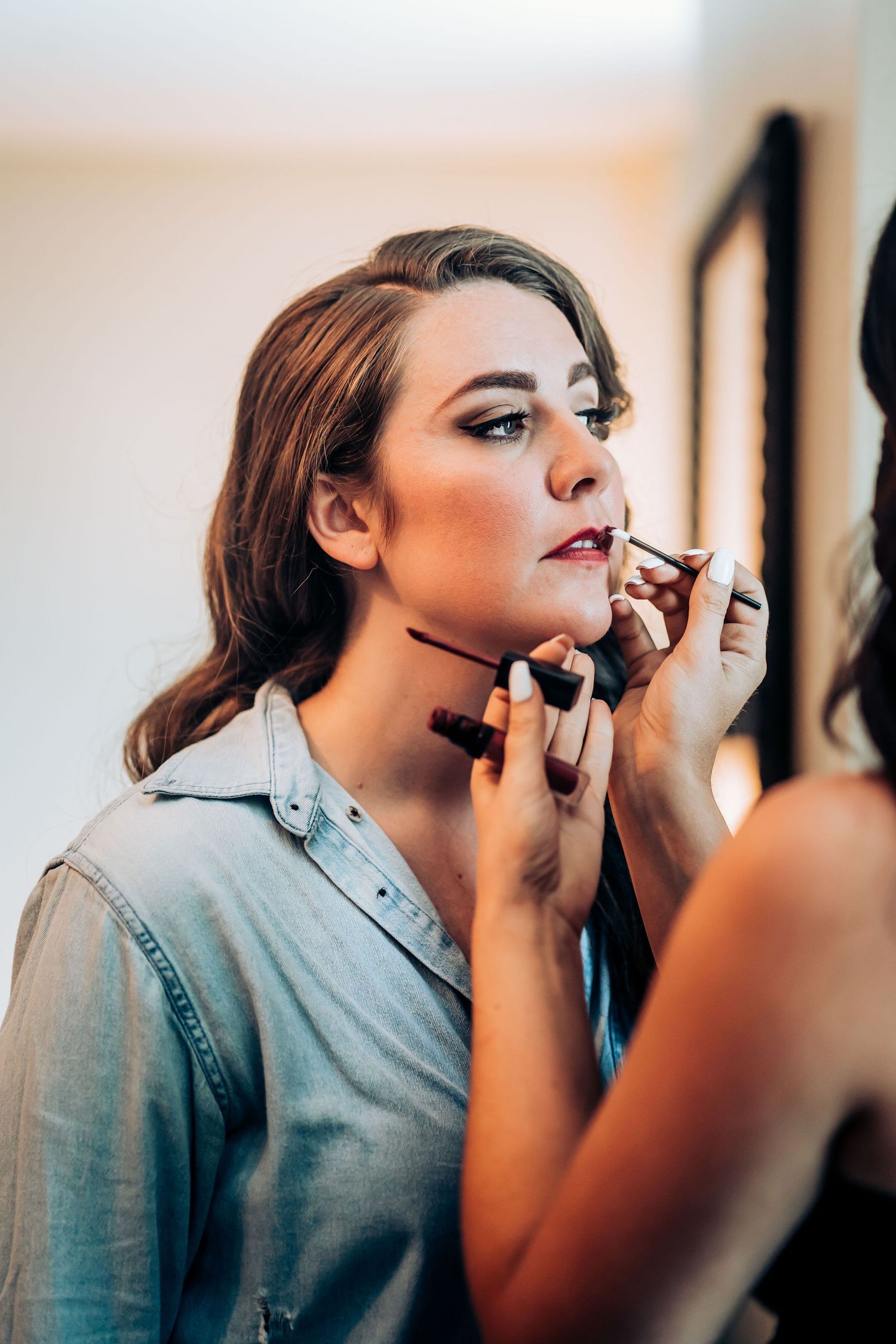 Close-up of makeup application with brushes and cosmetics in natural lighting.