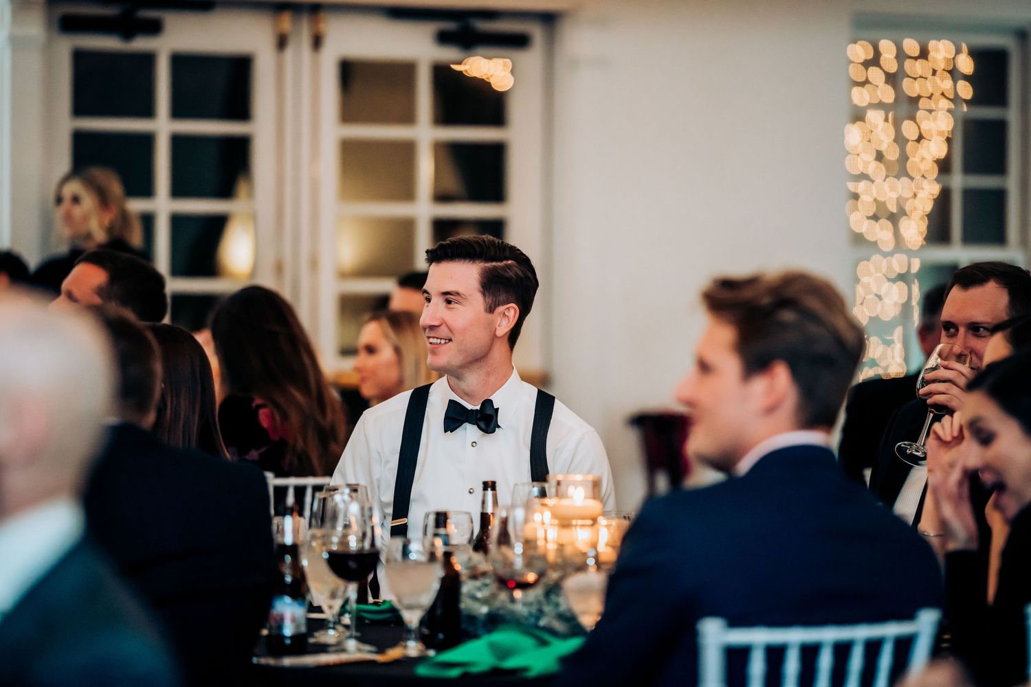 Candlelit wedding reception dinner with guests seated at elegant tables with crystal decor.