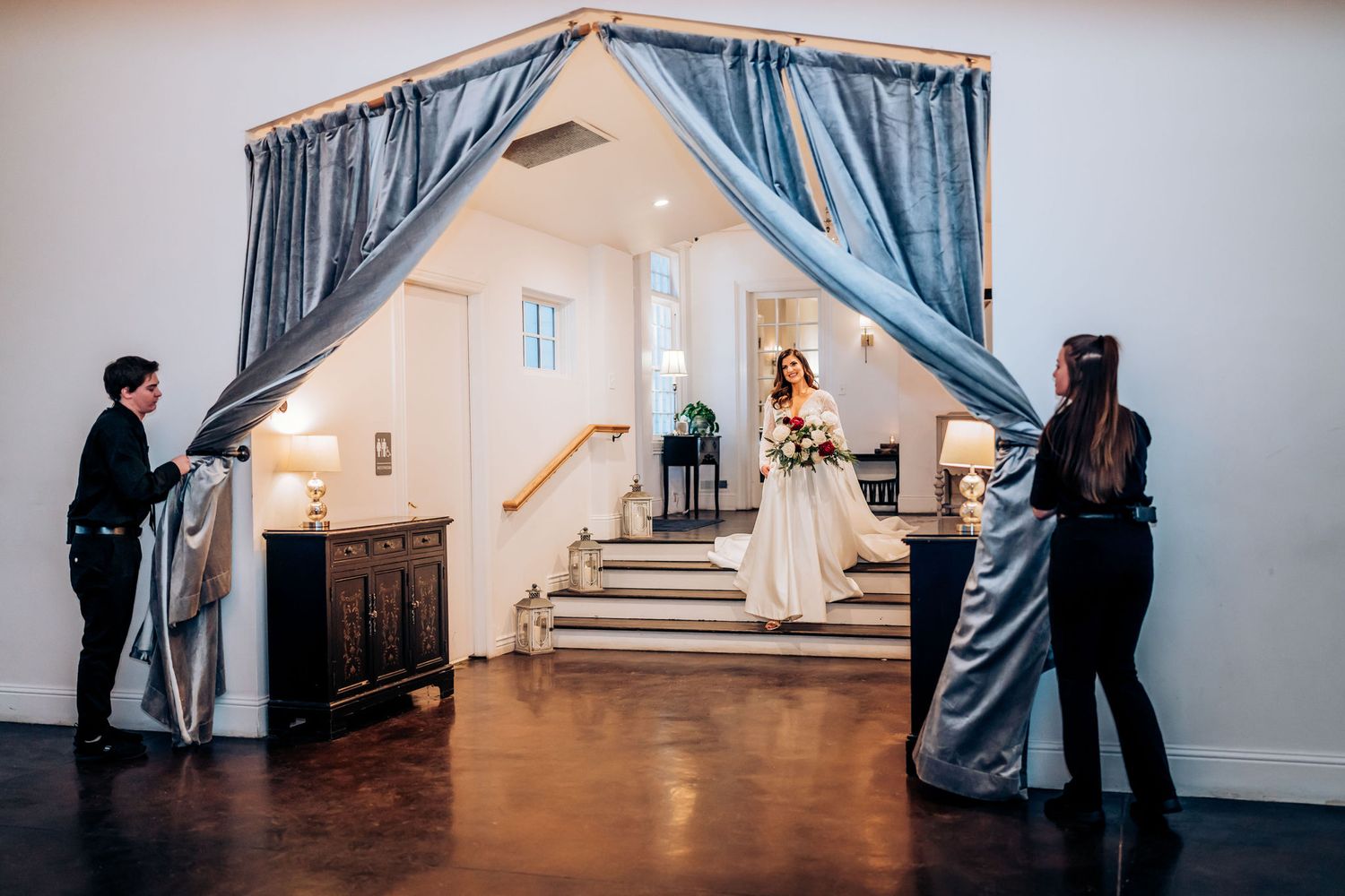 Wedding venue features elegant grey drapes framing a grand entrance with stairs.