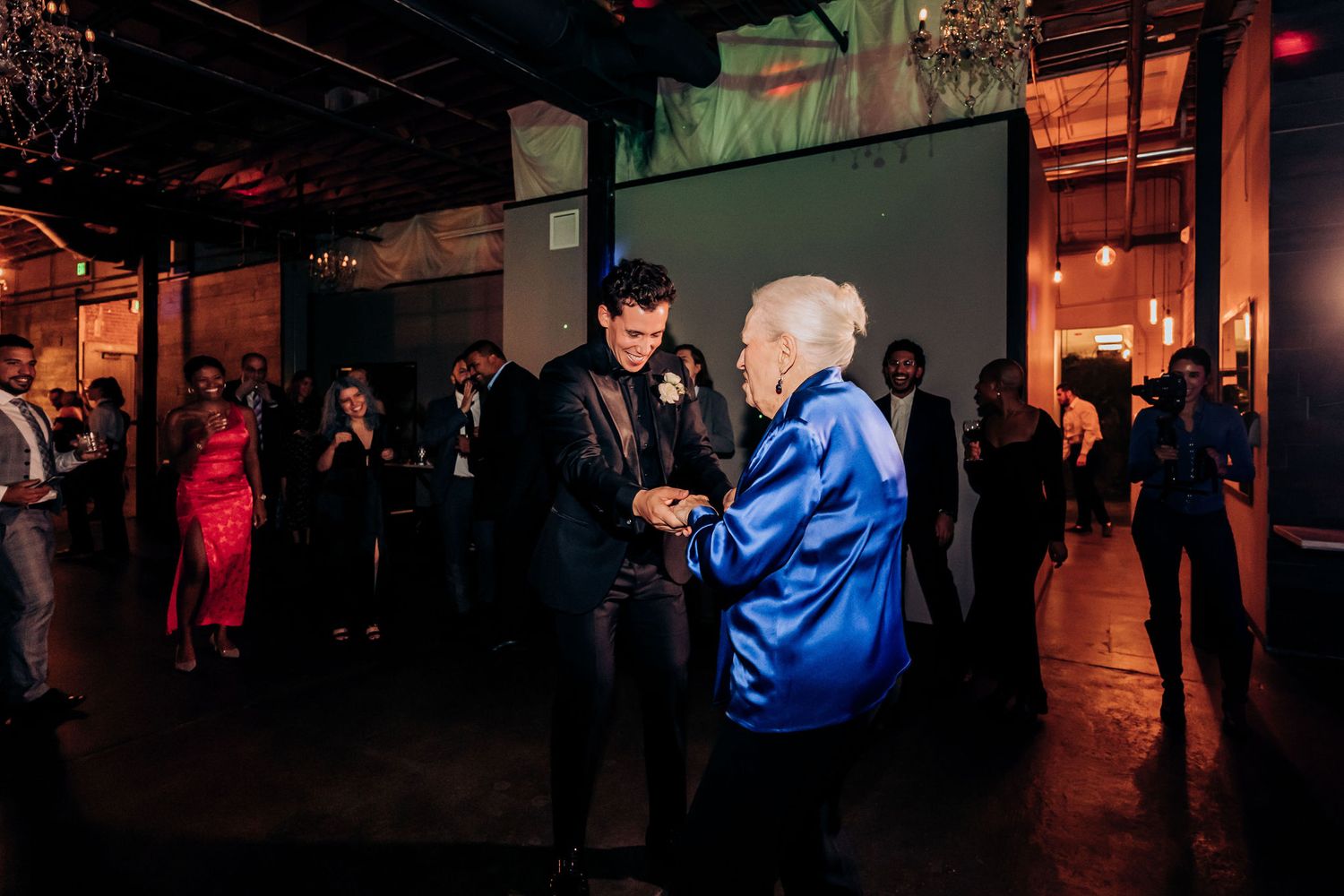 Guests enjoying dance floor moments at dimly lit wedding reception venue.