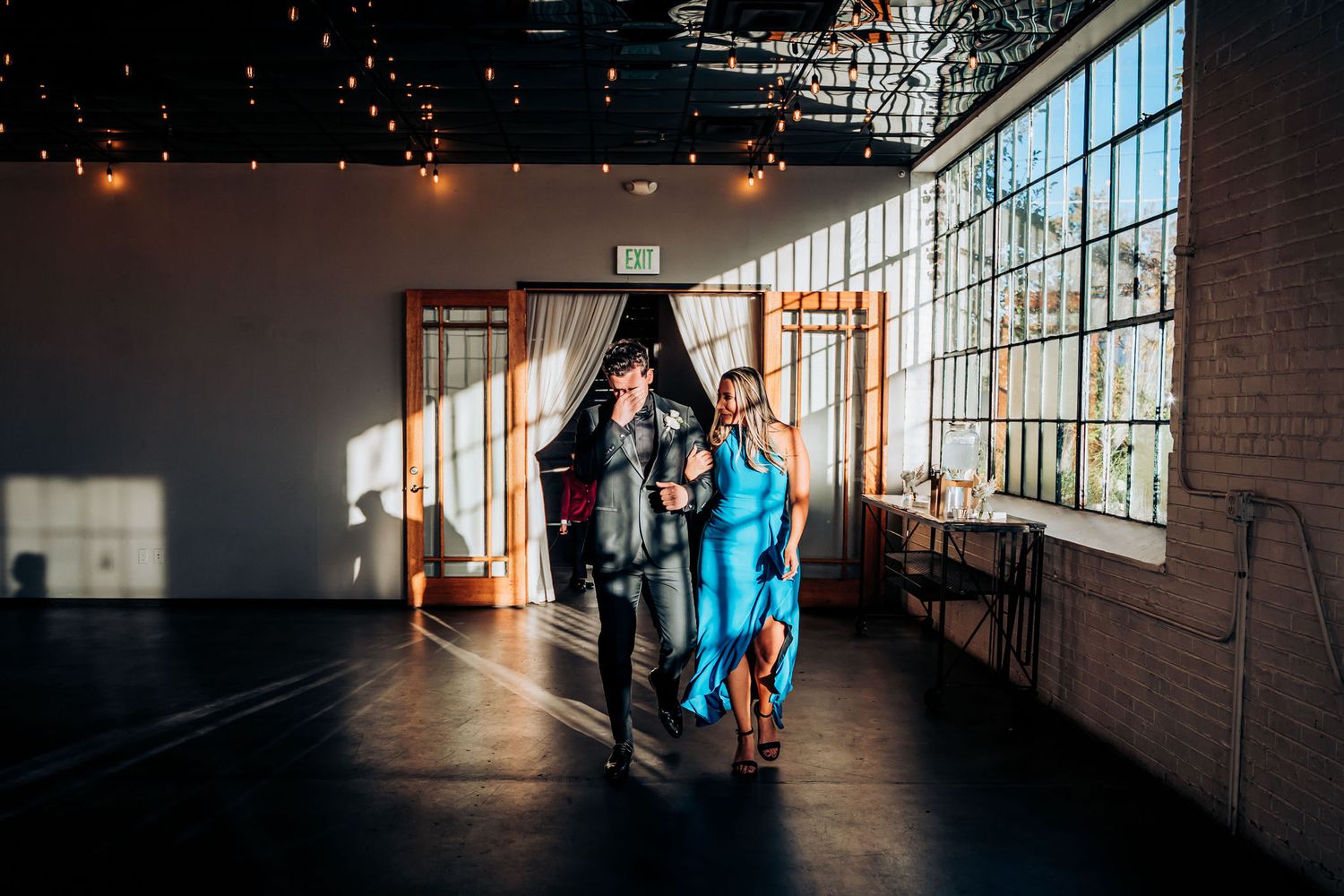 Wedding guests entering a modern industrial venue with large windows.