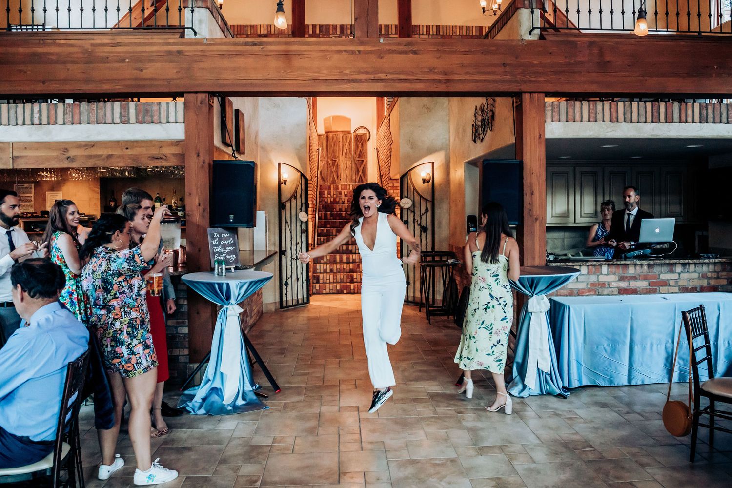 Guests gather inside an elegant venue with wooden beams and blue table settings for a wedding celebration.