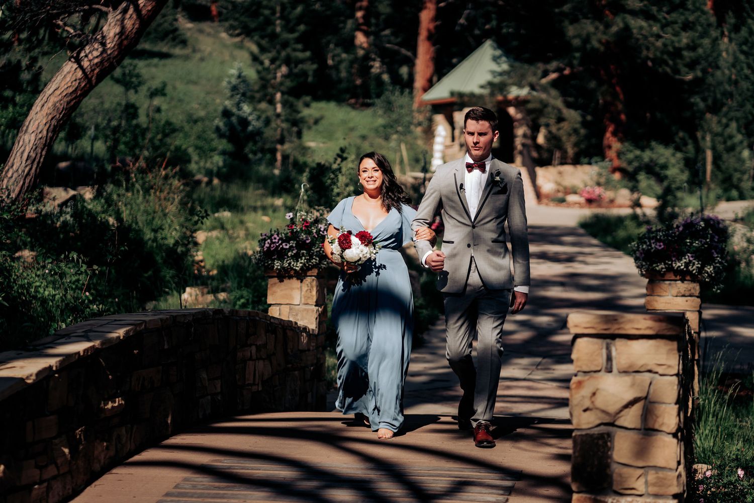 Couple walking together on a stone pathway through a mountain garden.