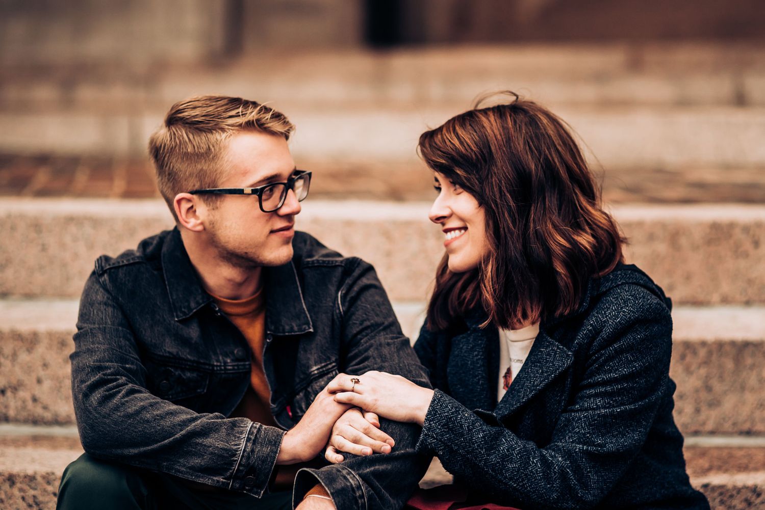 A couple shares a happy moment sitting on stone steps outdoors.