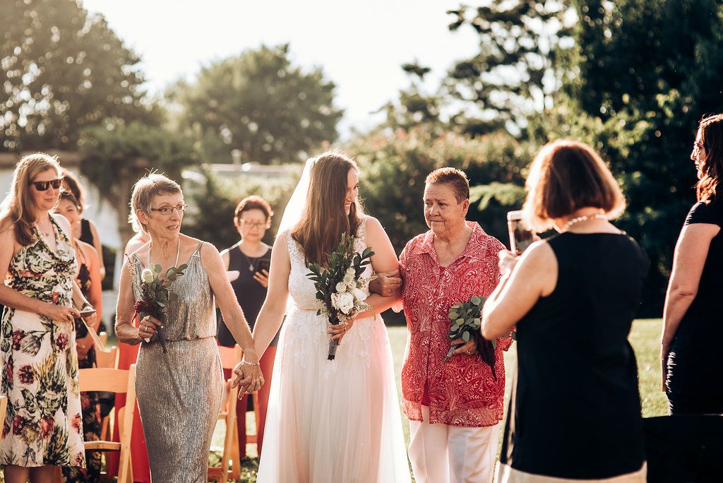 Wedding guests gather outdoors during golden hour, sharing joyful conversation at a summer celebration.