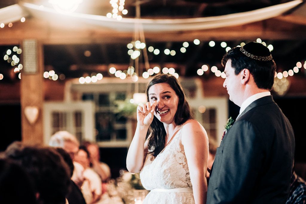 Joyful reactions during reception speeches in rustic venue with string light decor.