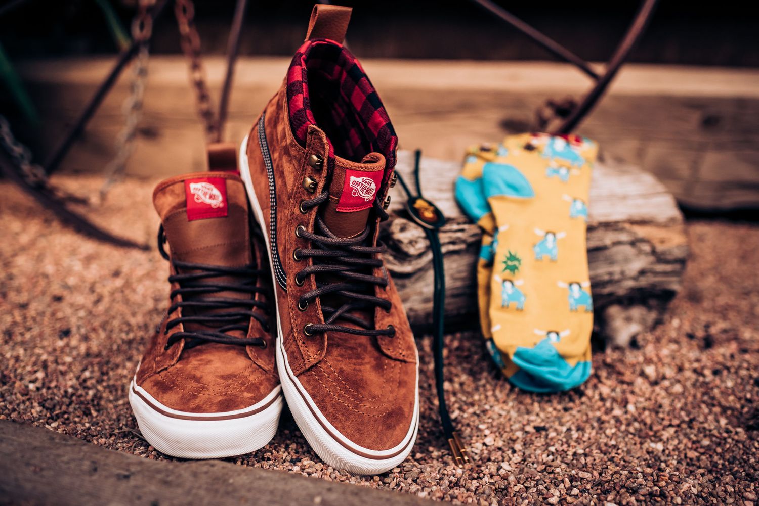 Brown suede high-top sneakers next to colorful patterned socks on wooden surface.