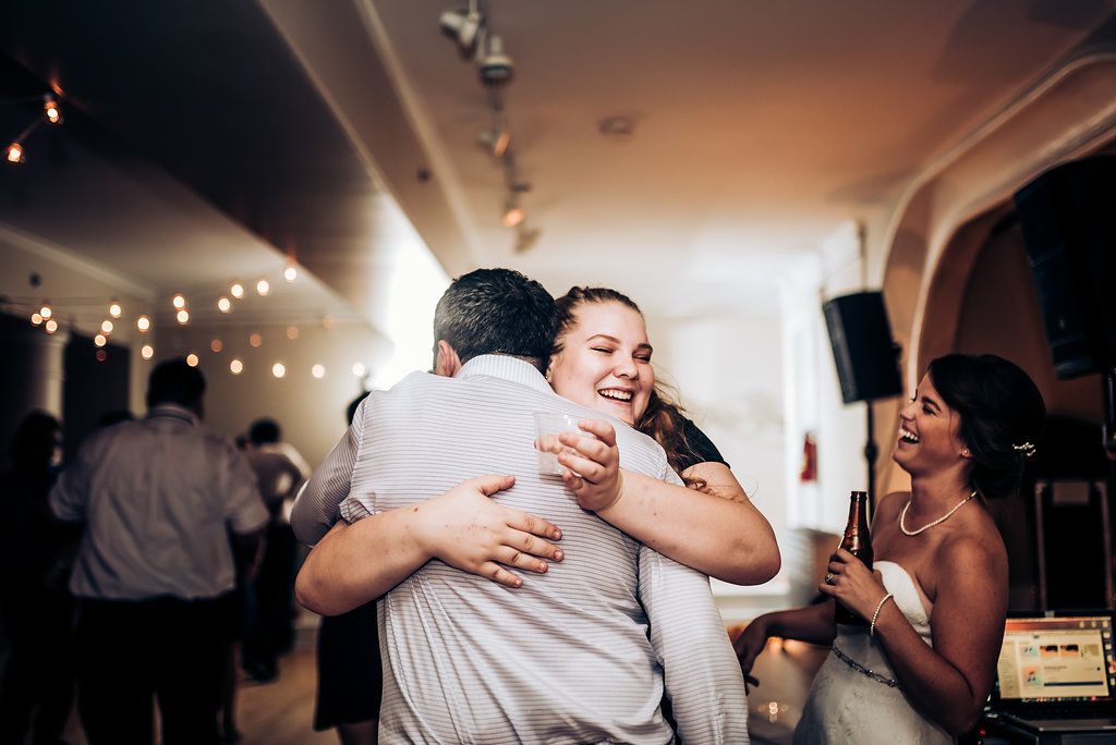 Candid moment of guests embracing and laughing during a dance party celebration.