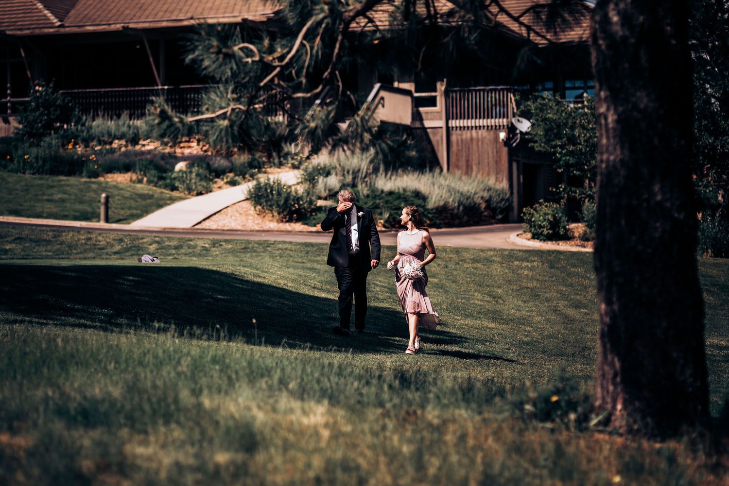 Couple walks through garden pathway on sunny afternoon.