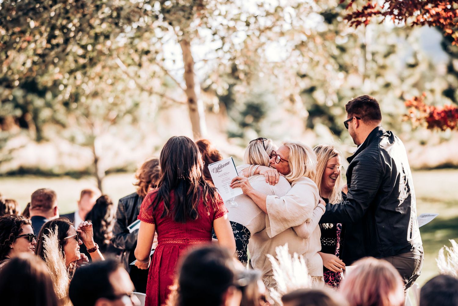 Wedding guests gathered outdoors celebrating with raised glasses during a fall ceremony.