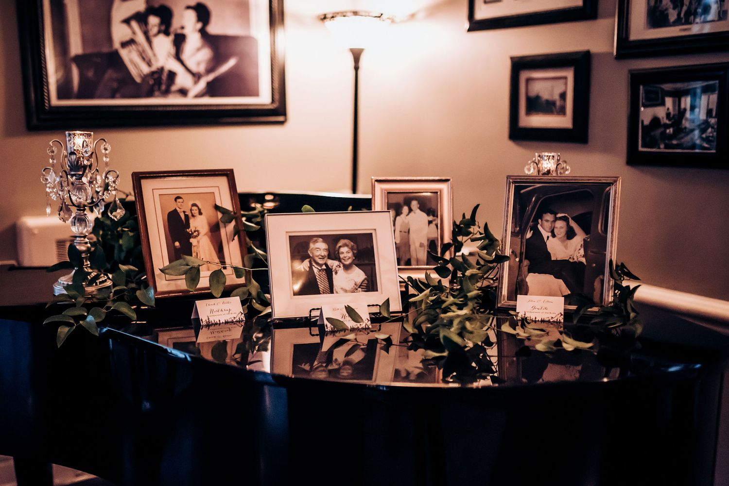Wedding memory table displays vintage family photos with greenery decorations.
