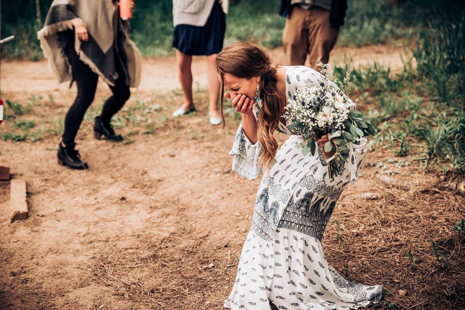People dancing and celebrating on a dirt path surrounded by nature.