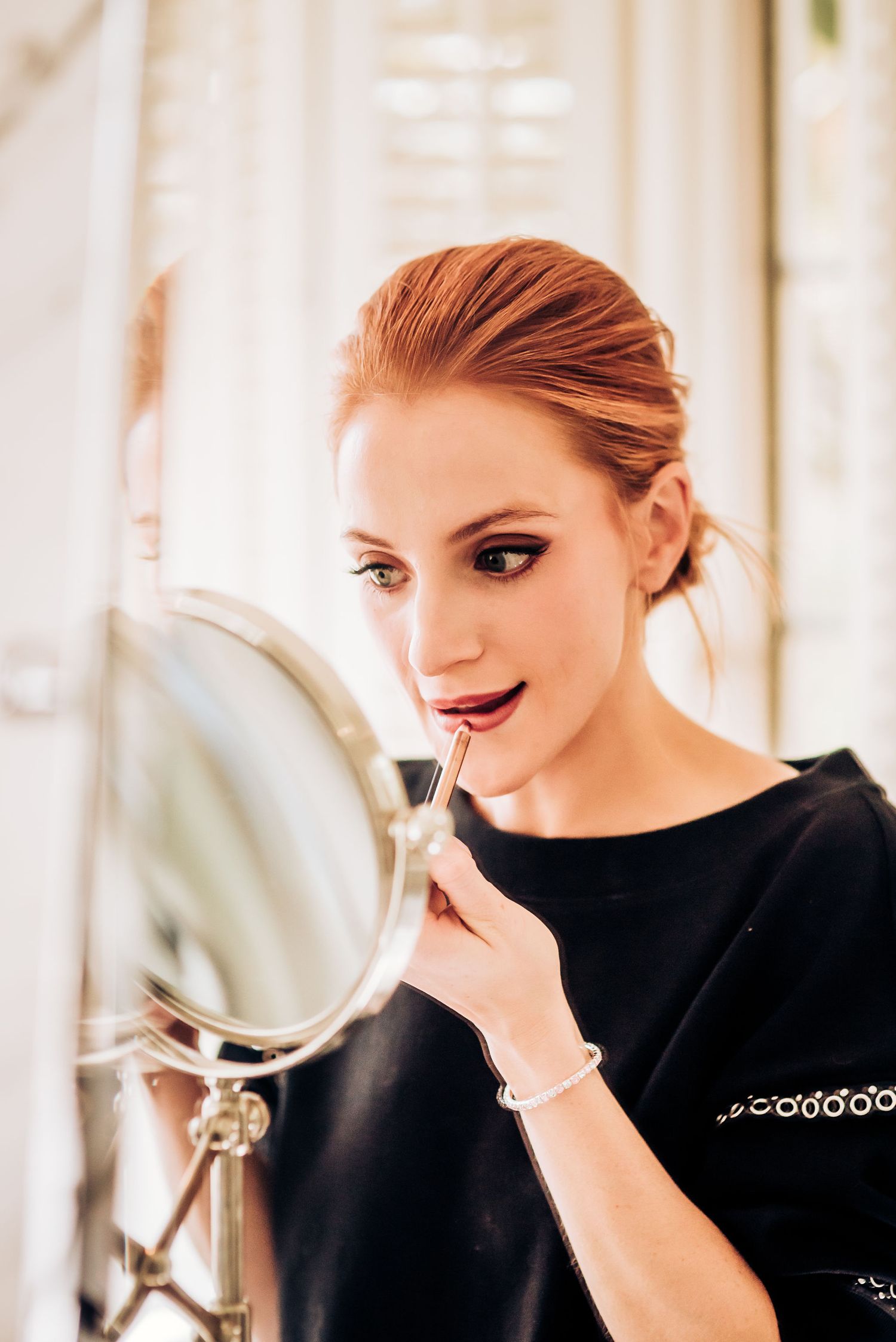 Someone applying makeup while looking in a vanity mirror.