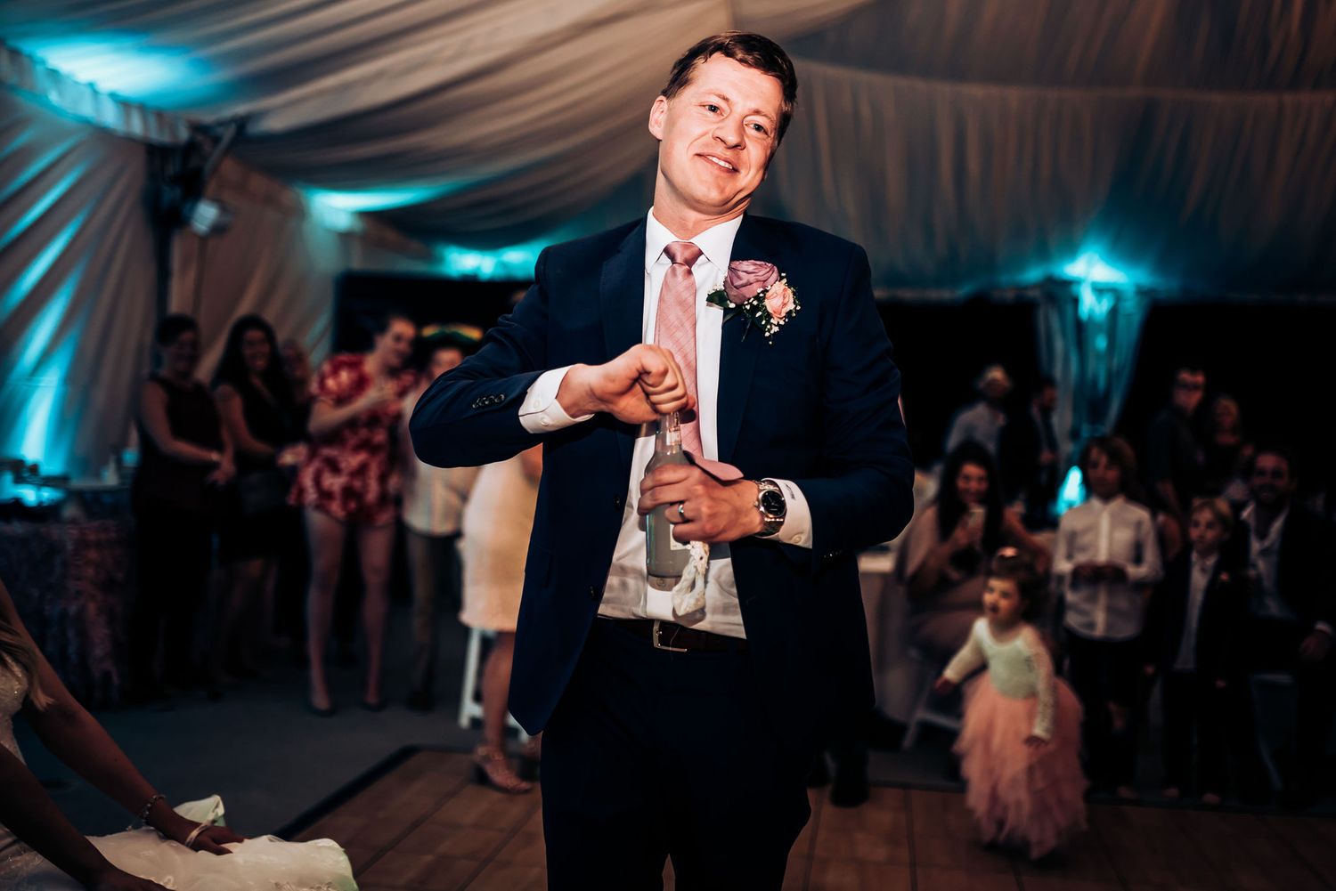 Guest delivering a celebratory speech at a wedding reception under decorated tent lighting.