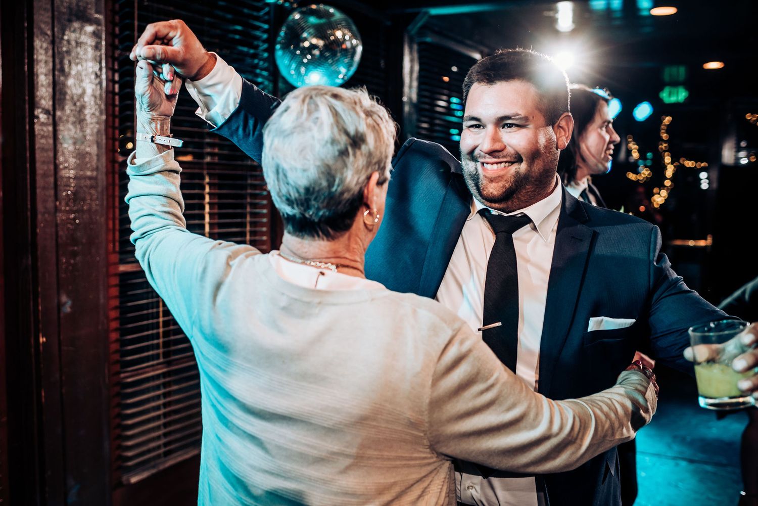 Two people dancing and celebrating under blue disco lights at an indoor venue.