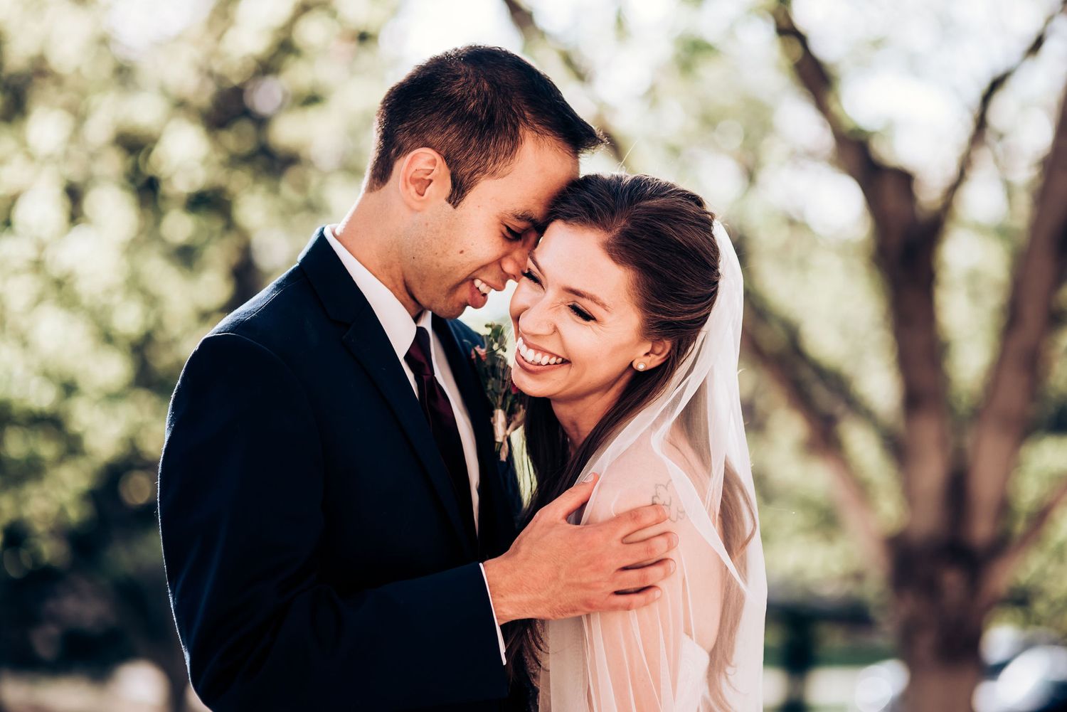 Romantic wedding moment captured between elegant stone pillars outdoors.