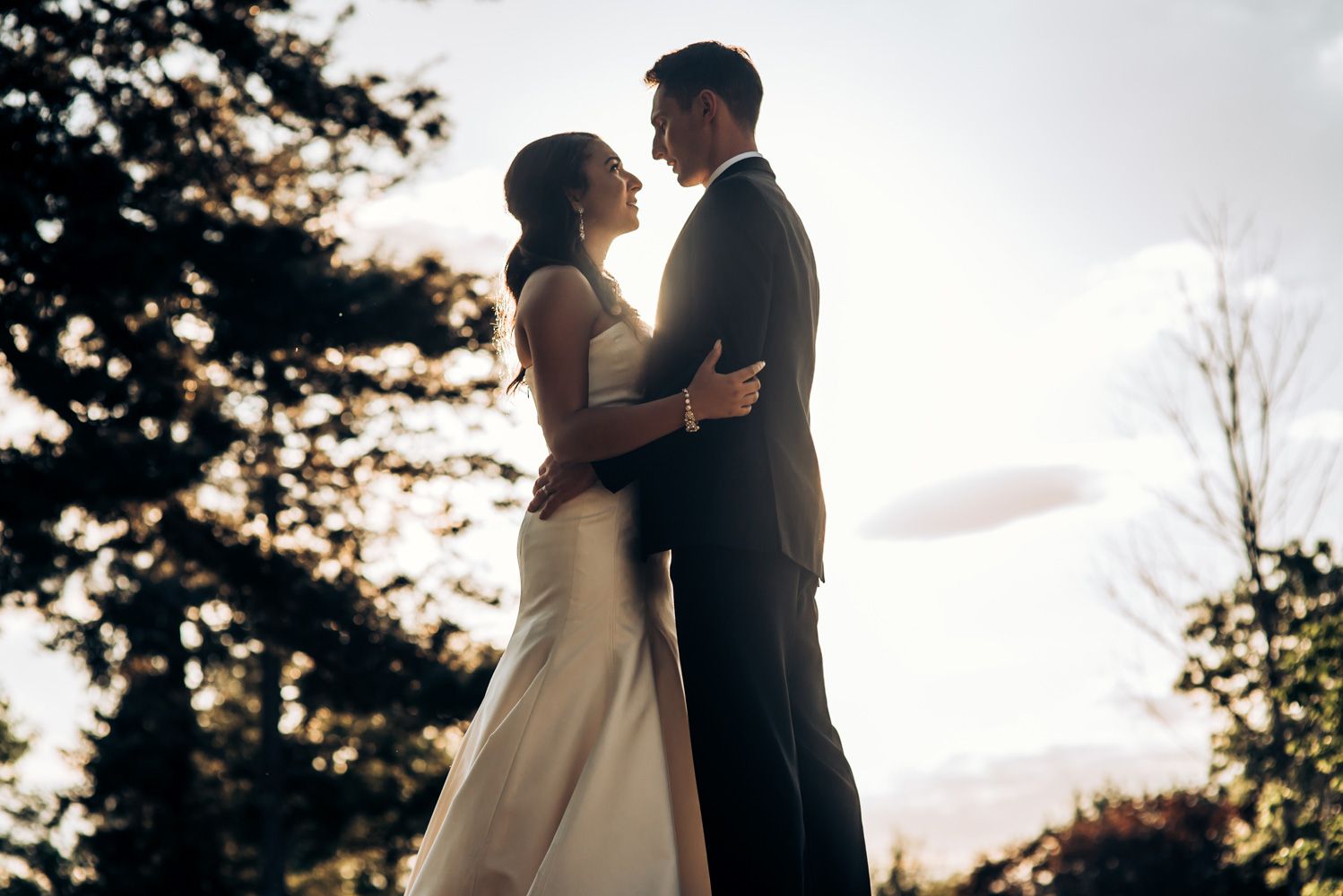 Romantic silhouette of couple embracing at sunset during wedding photoshoot.
