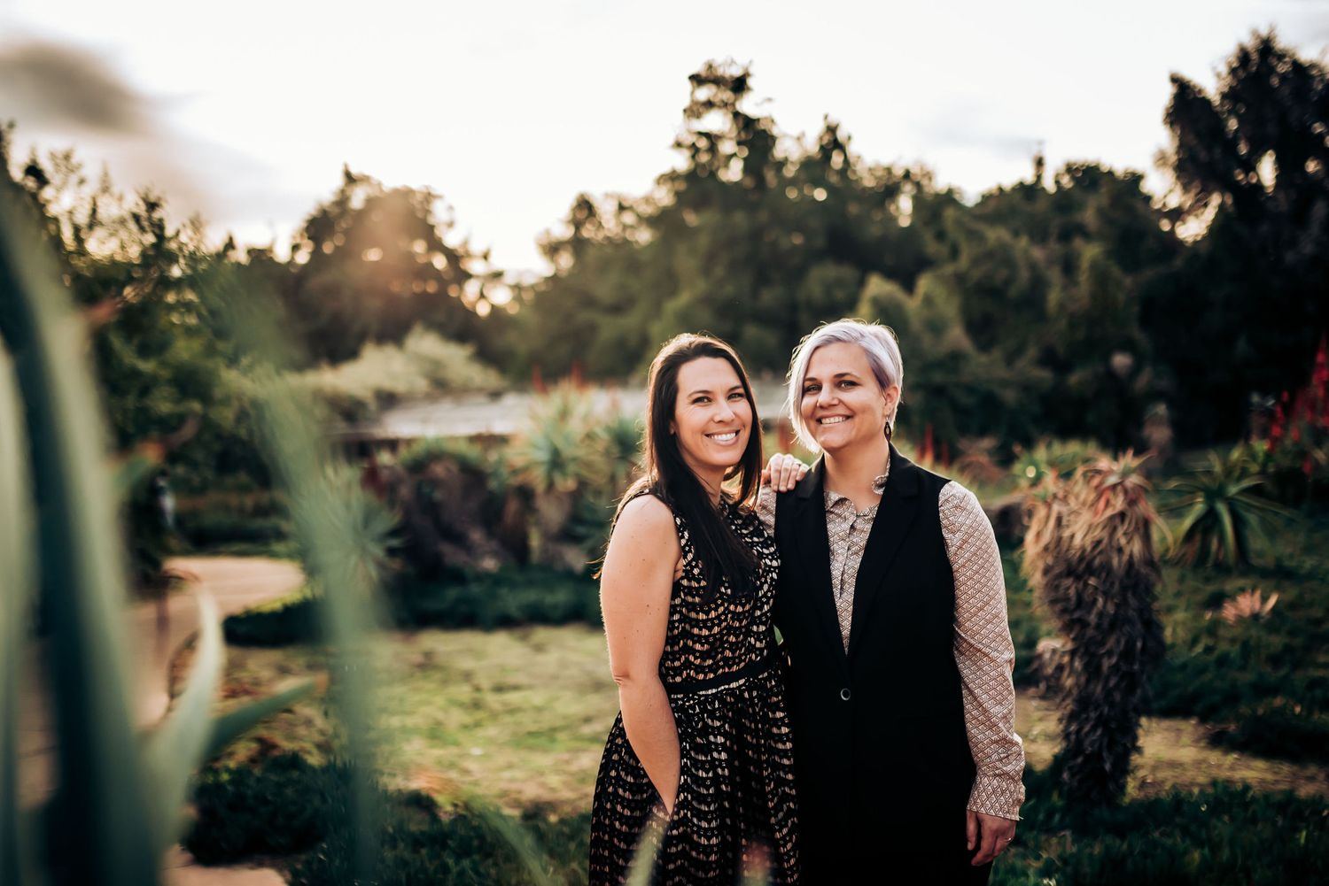 A tender moment captured in a garden setting with warm sunset lighting.