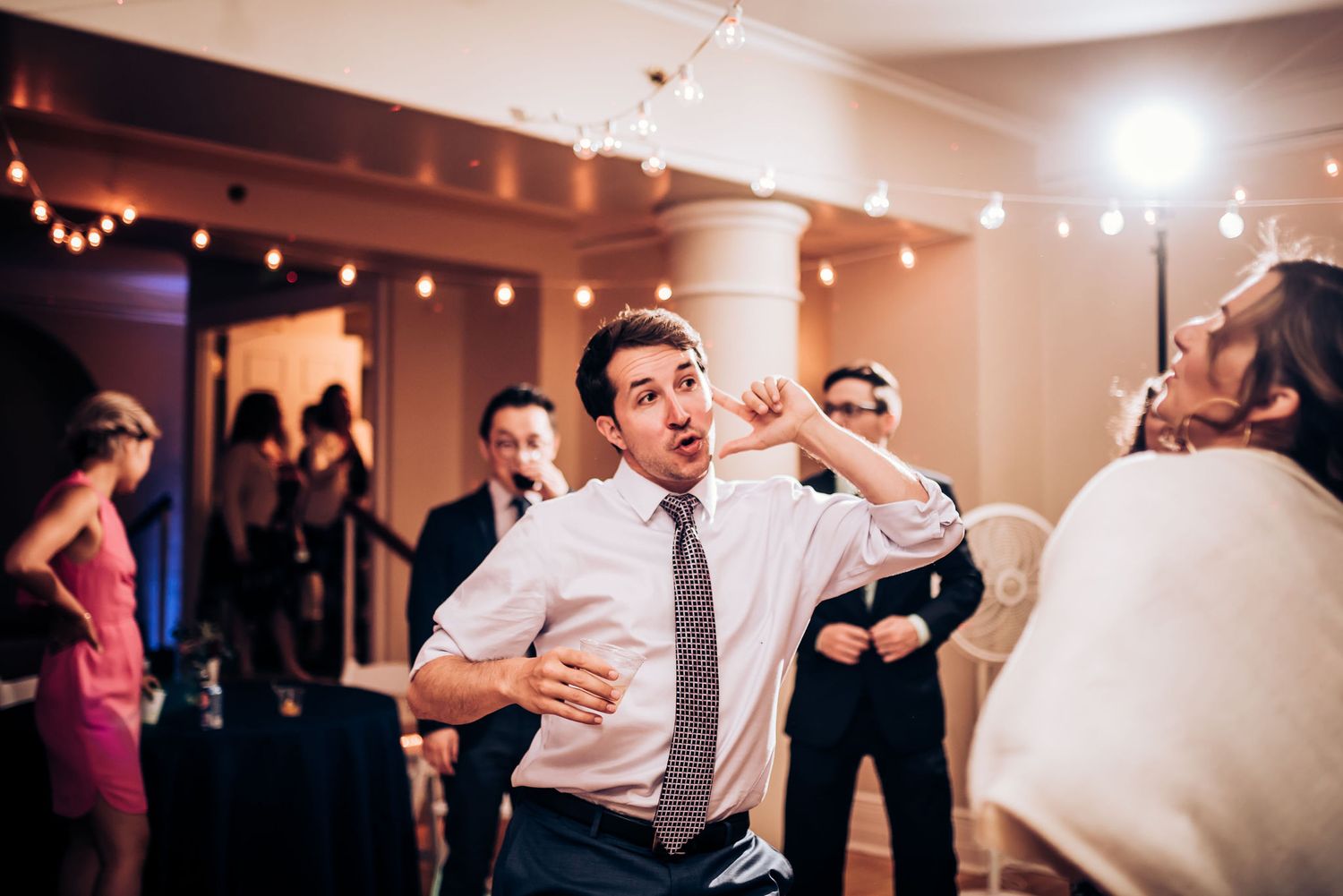 Guest shows off dance moves at indoor celebration while others watch and smile.