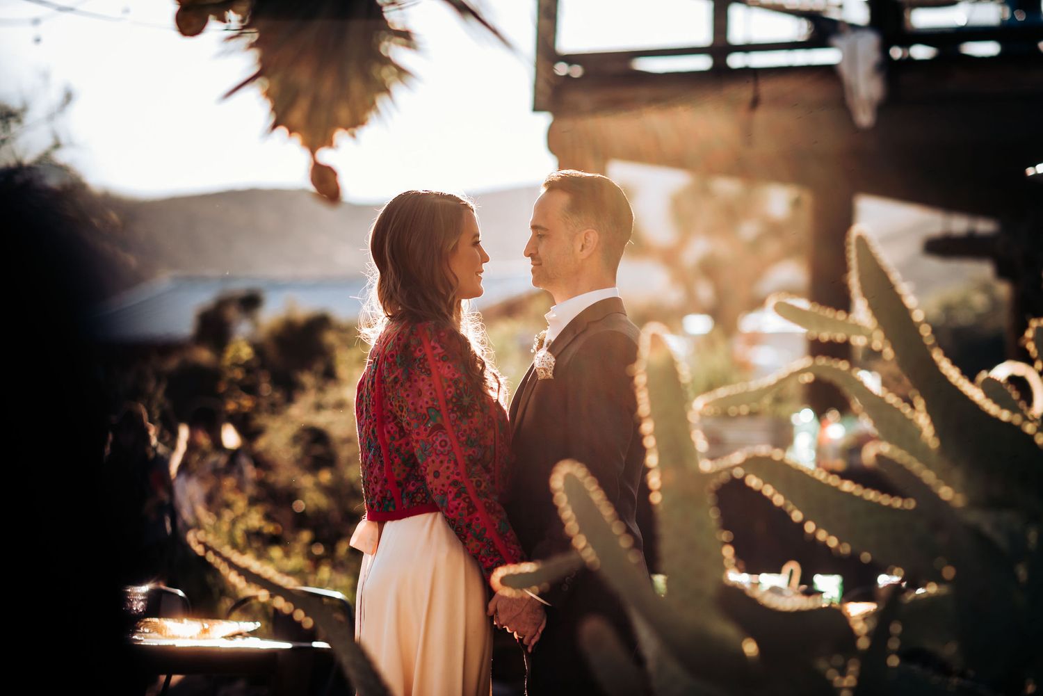 A romantic silhouette of a couple in a desert garden setting at sunset.