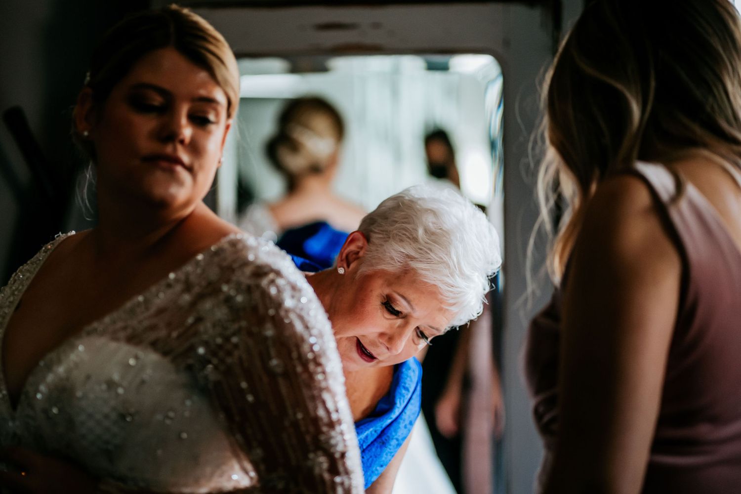 Wedding party members gather in preparation before the ceremony in an intimate indoor setting.