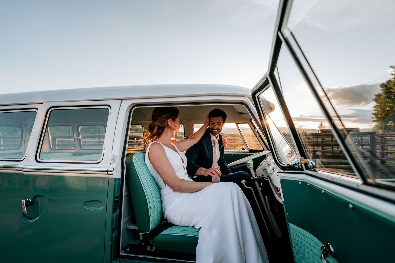 Couple sitting in front seats of vintage turquoise Volkswagen van during sunset photoshoot.