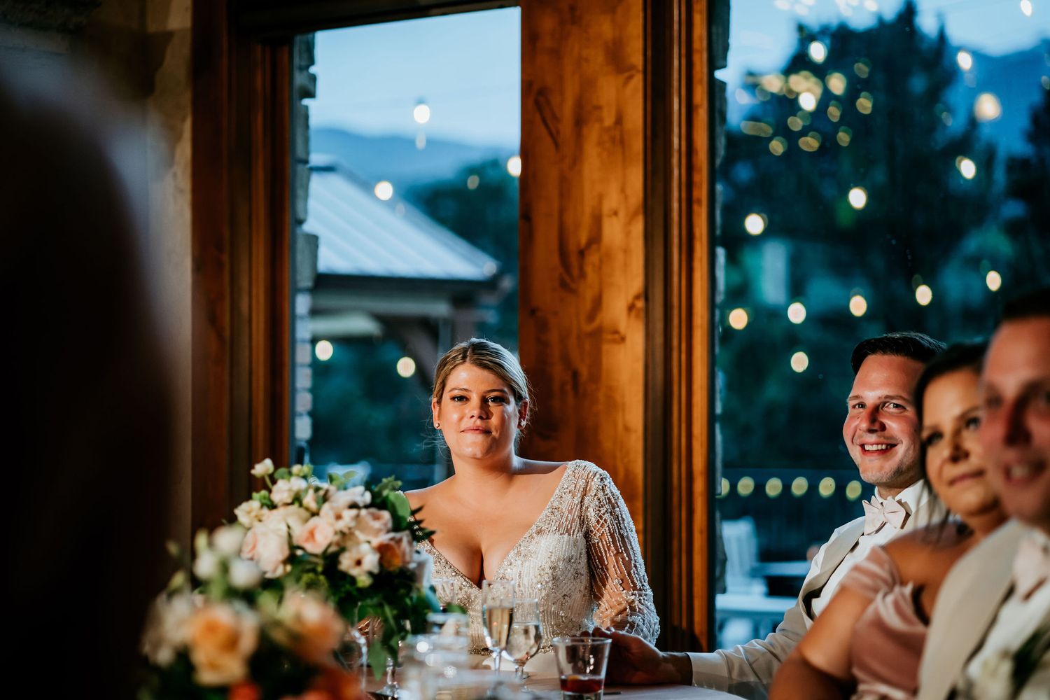 Reception dinner scene with elegant table settings and warm lighting in rustic venue.