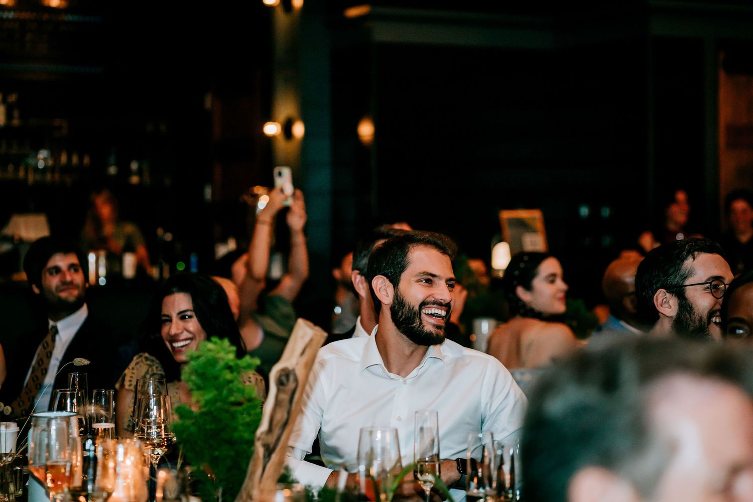 Guests laugh and celebrate during an evening dinner reception.