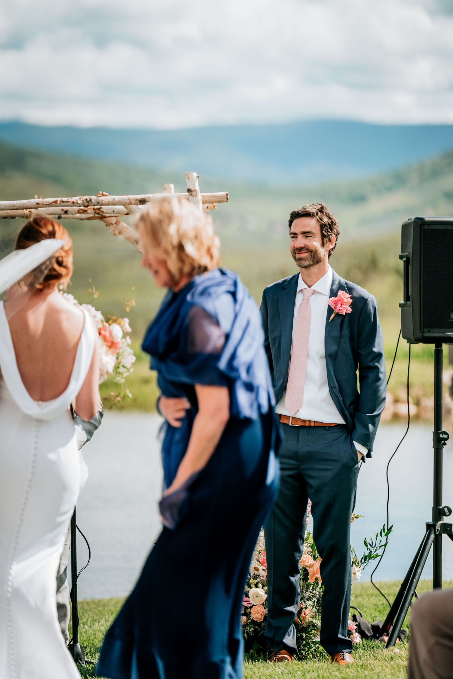 Mountain wedding ceremony with rustic wooden arch and scenic valley views.