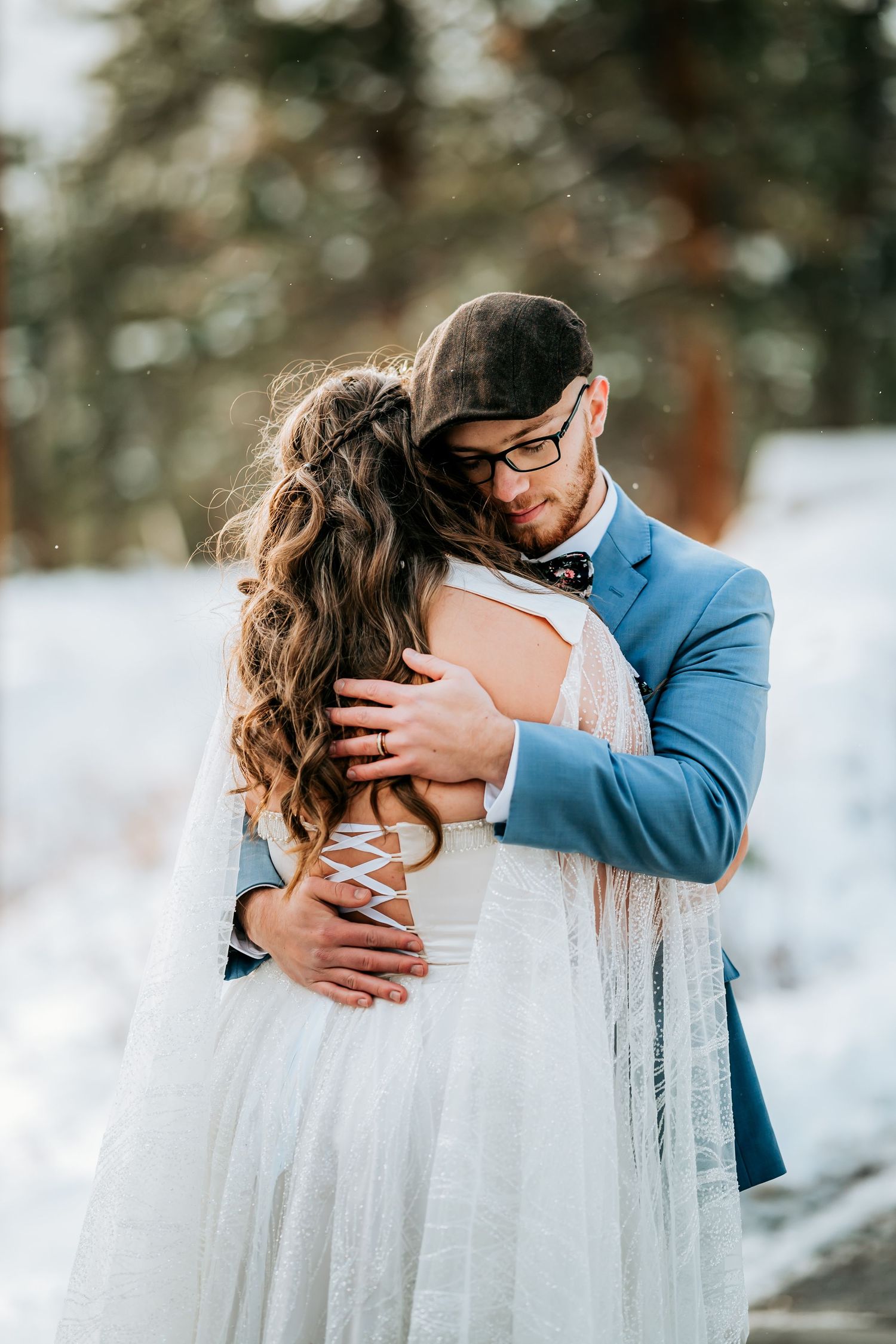 Intimate winter wedding moment with bride in white lace dress and groom in blue suit.