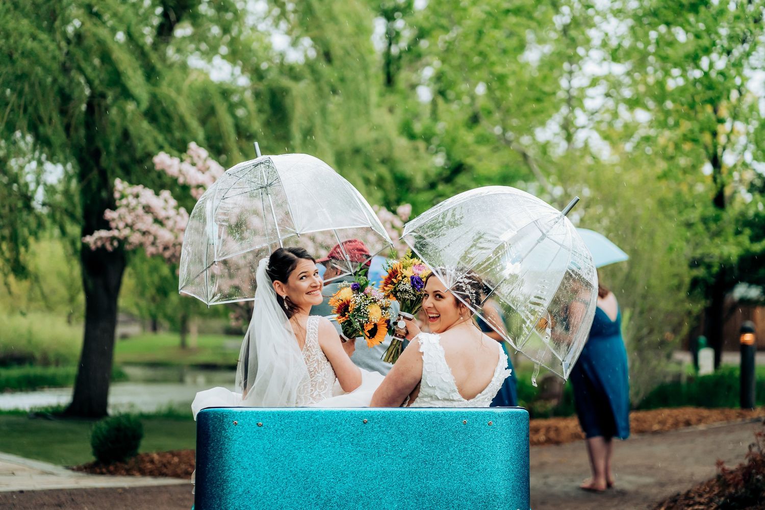 Wedding couple shares playful moments on a turquoise bench in a garden setting.