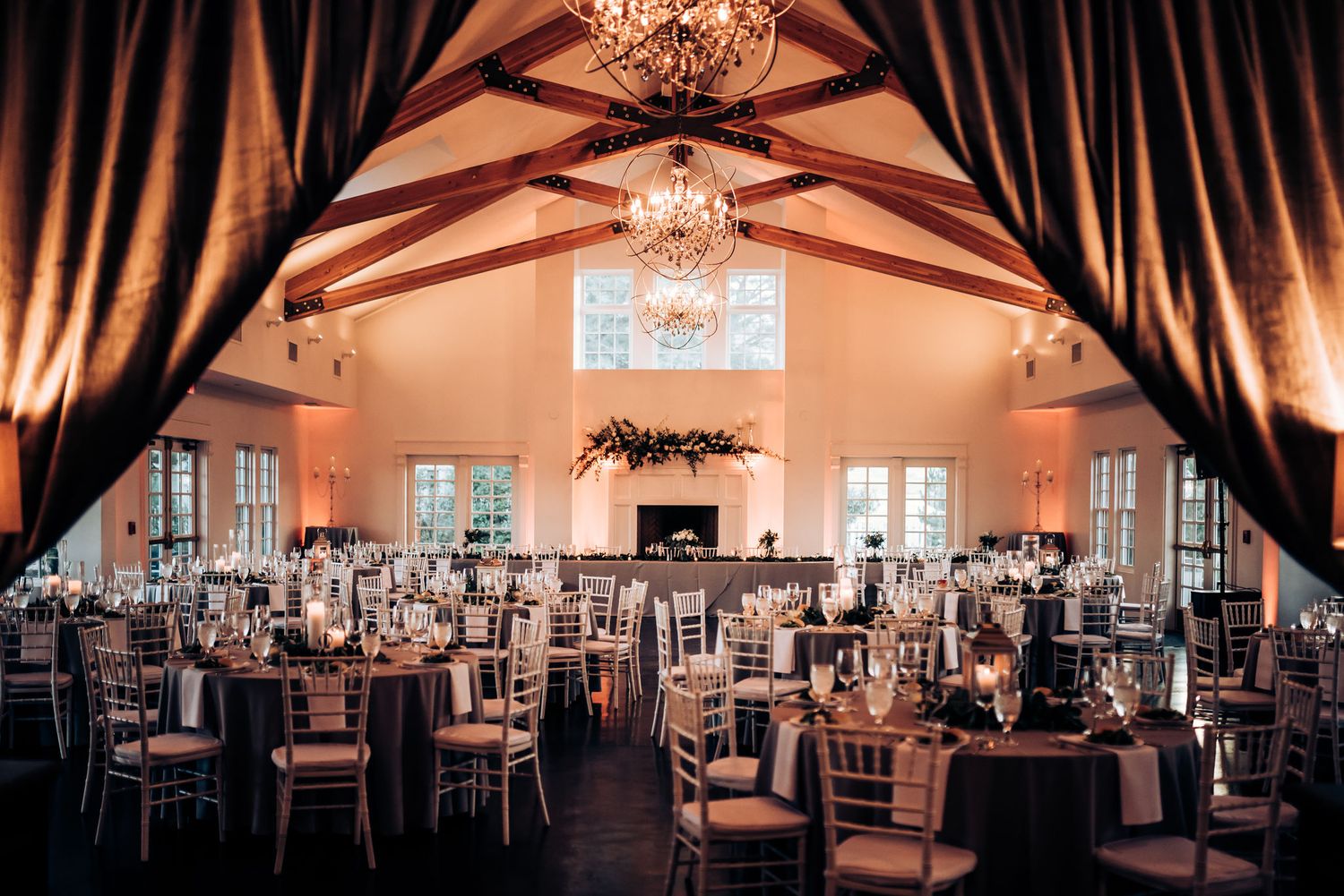 Elegant wedding reception hall with chandeliers and dramatic drapes.