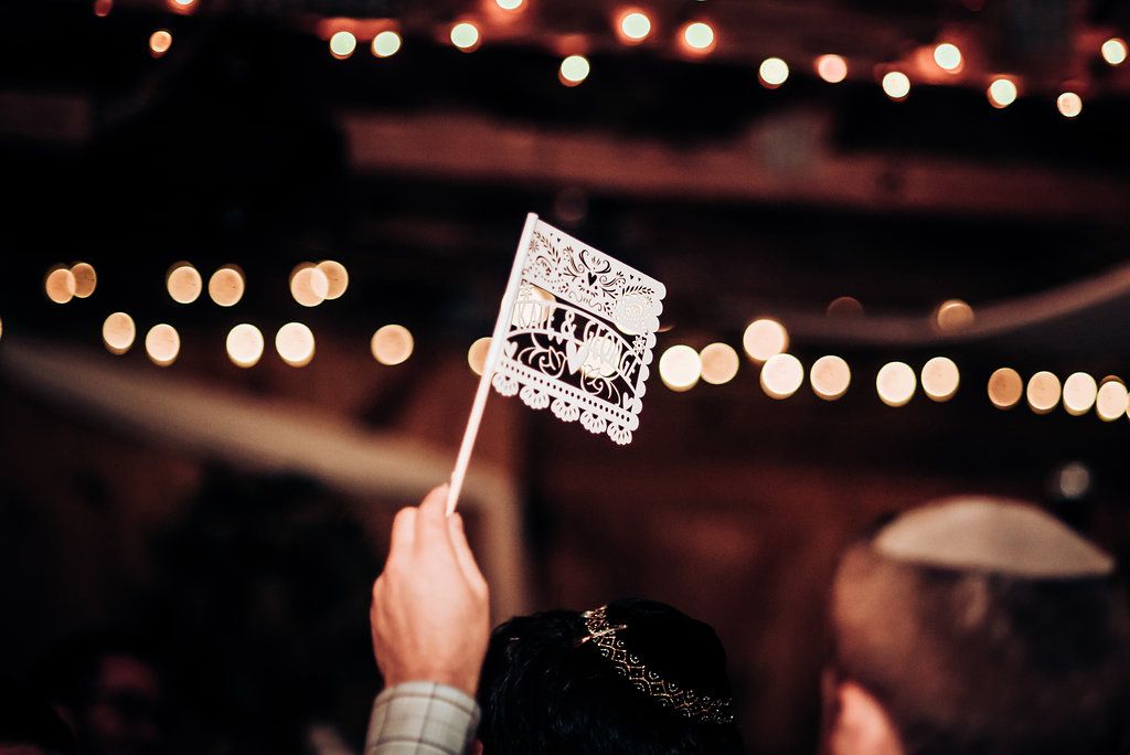 Hand holds up a paper sign against bokeh lights at an evening celebration.