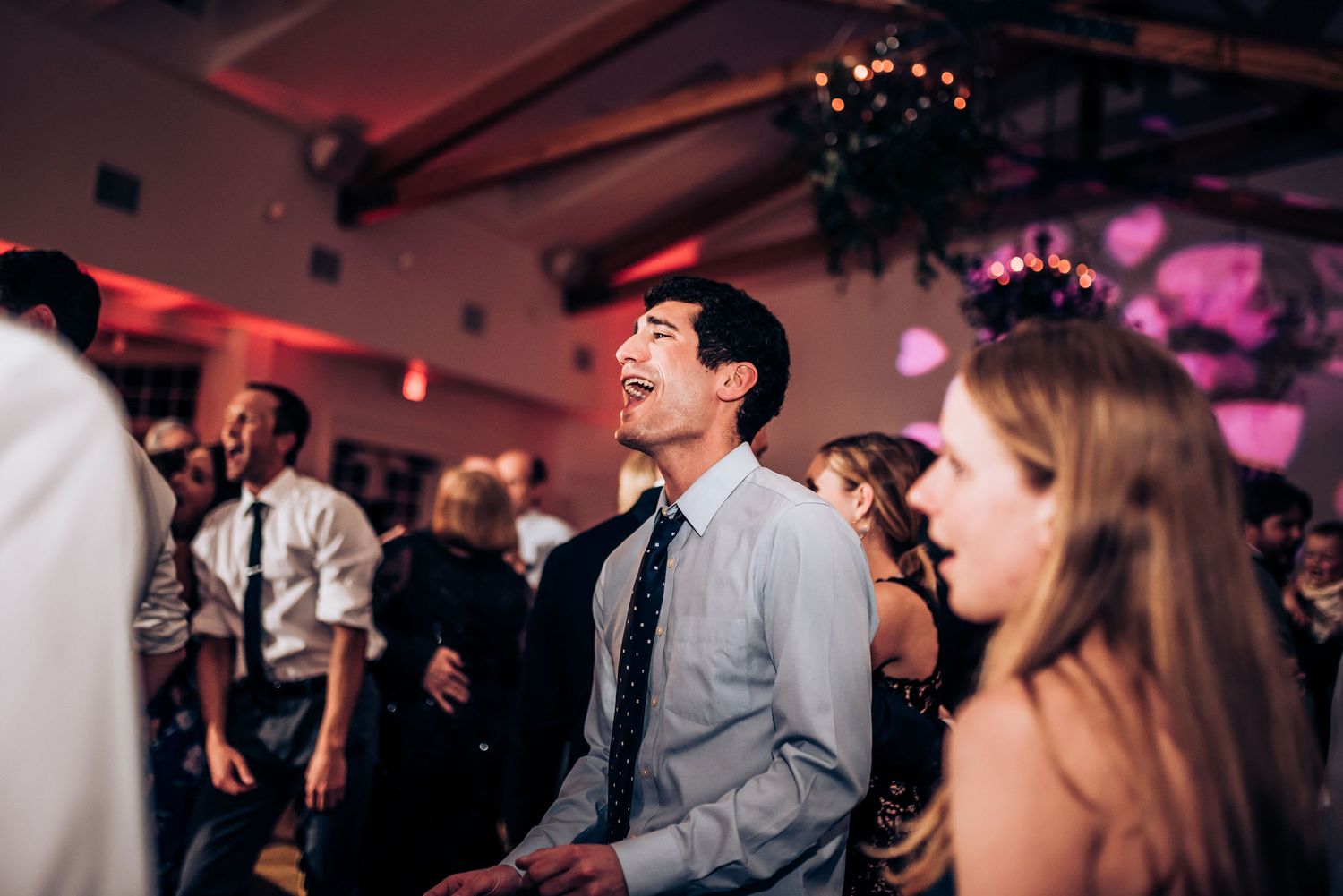 Guest enjoying themselves on crowded dance floor at wedding reception.